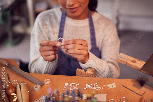 Close Up Of Female Jeweller At Bench Checking Ring She Is Working On In Studio