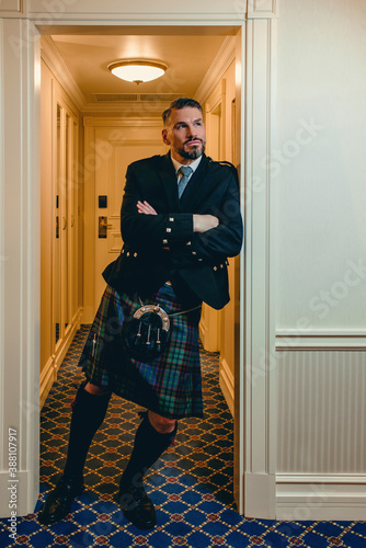 handsome mature courageous stylish man (gay) scotsman in kilt in fancy hotel room. Style, fashion, lifestyle, culture, travel, ethnic concept.