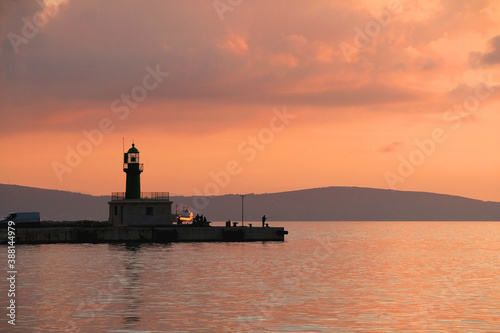 Beautiful sunset over the sea with lighthouse silhouette, in Split, Croatia.