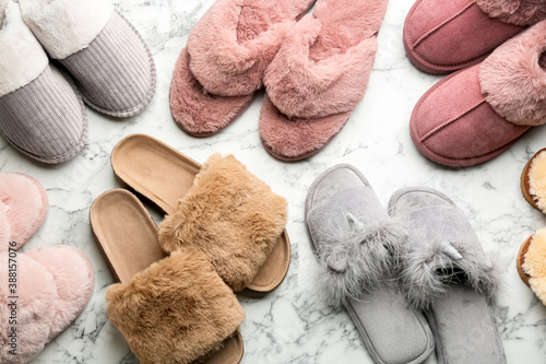 Many different soft slippers on white marble background, flat lay