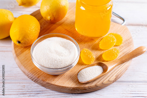 Jelly yellow candies made from gelatin powder, agar-agar (vegetarian substitute for gelatin) and pectin powder on wooden board.