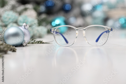 Christmas eyeglasses blue spectacles isolated on white table with balls and decorations, useful as a greeting gift card template with copy space 