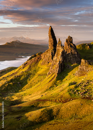 The Old Man of Storr rock pinnacles at sunrise with vibrant Summer sunlight from the morning sun and dramatic clouds overhead. Isle of Skye, Scotland, UK.