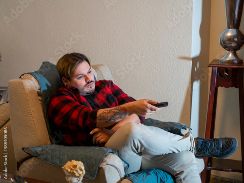 Hombre aburrido viendo la televisión en casa por el confinamiento y el toque de queda