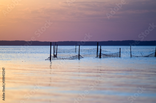 Krajobraz morski z rozstawionymi sieciami połowowymi na tle zachodzącego słońca