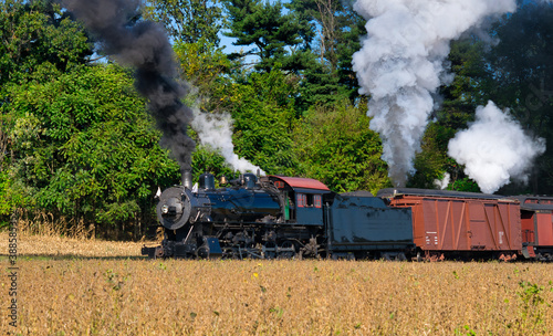 Close up of an Antique Steam Freight Train Puffing Smoke and Steam While going Thru Amish Countryside