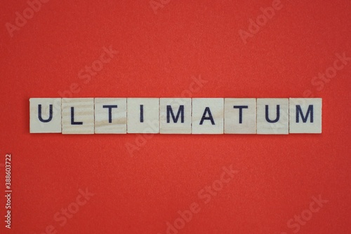 text the word ultimatum from gray wooden small letters with black font on an red table