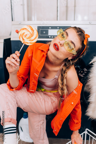 fashionable woman holding sweet lollipop in laundromat