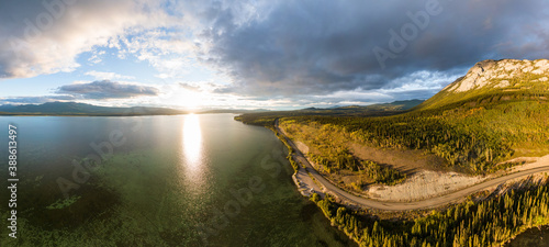 Beautiful Panoramic View of Golden Mountain and Forest beside Scenic Lake at Sunset in Canadian Nature. Aerial Drone Shot. Taken near Atlin, Yukon, Canada.
