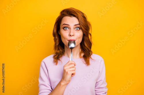 Portrait of astonished inspired girl have weekend in restaurant taste dish enjoy lick spoon impressed stare stupor wear pink jumper isolated over yellow color background