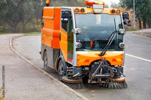 A hydraulically powered road sweeper sweeps the street.