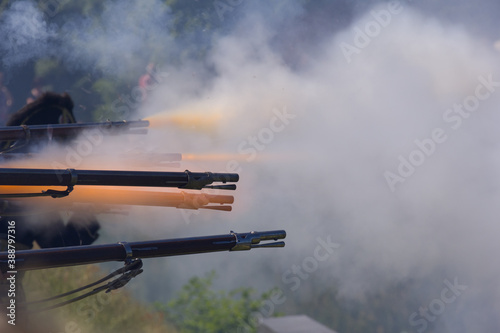 flintlock muzzle loader muskets guns firing. Smoke from the gunpowder fills the air.