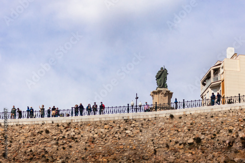 Spain; Oct 2020: People enjoying the sea views at the famous balcony "Balcó del Mediterrani". Statue of admiral Roger de Lauria behind. Popular landmark sites at the city of Tarragona, Catalonia Spain