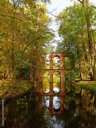 akwedukt z cegieł odbijający się w rzece wśród drzew w parku jesienią