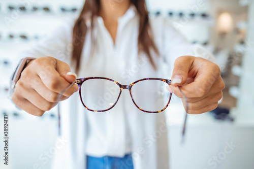 Optician giving new glasses to customer for testing and trying. Eye doctor showing patient lenses. Professional optometrist in white coat. Female doctor in ophthalmology clinic..