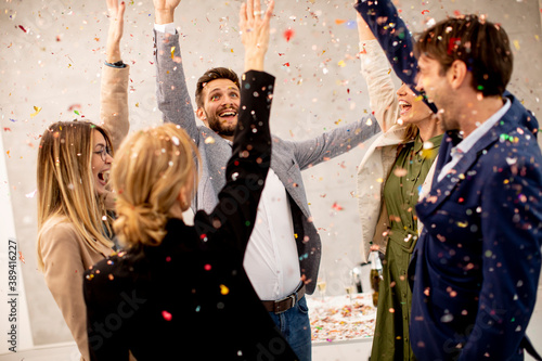 Group of business people celebrating and toasting with confetti falling in the office