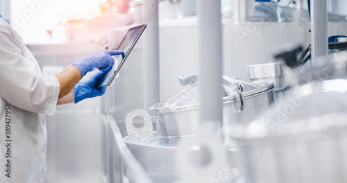 Concept food industry banner. Factory worker inspecting production line tanker in of dairy factory with computer tablet