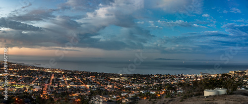 Ventura coast along the Pacific Ocean shines with city lights and colorful clouds before sunrise.