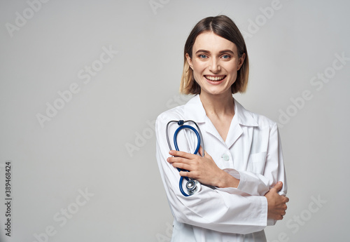 A professional doctor in a medical gown holds a stethoscope in his hand