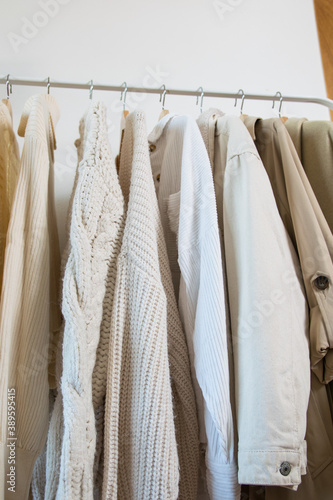 closeup of warm clothes of light colors like beige or white for winter hanging and clean on hangers
