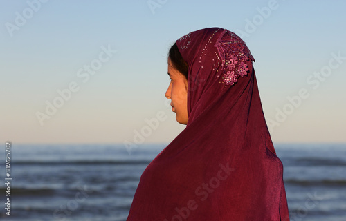 girl with purple veil on her head by the sea in summer