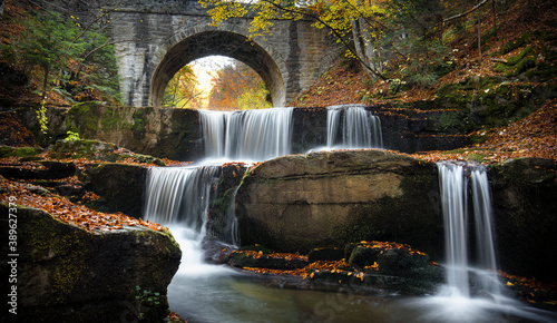 Autumn waterfalls near Sitovo, Plovdiv, Bulgaria. Beautiful cascades of water with fallen yellow leaves under the bridge. Sitovski waterfall