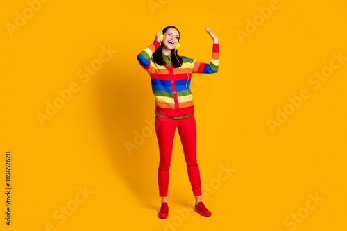 Full body photo of young cheerful girl listen music earphones look empty space isolated over yellow color background