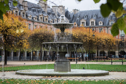 view of stoned fountain in vosges square in Paris by autumn