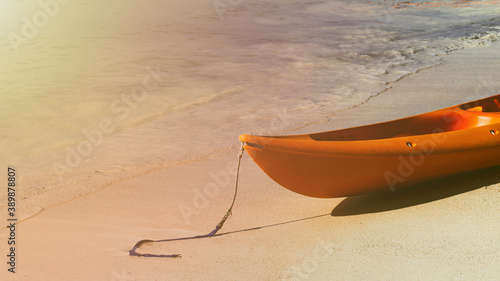 Orange Kayak boat at the side of the tropical sand beach island in Malaysia with sun flare light. Travel and tourism concept in Southeast Asia. Wallpaper, brochure, banner, poster, flyer and template.