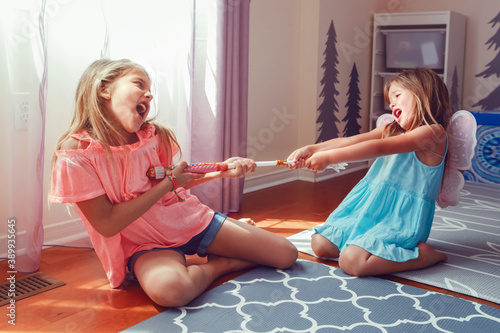 Two little mad angry girls sisters having fight at home. Friends girls can not share a toy. Lifestyle authentic funny family moment of siblings quarrel life. Kids bad behaviour.