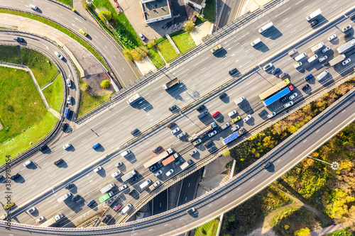 Aerial drone view of road interchange or highway intersection with busy urban traffic in modern city during sunny day. Traffic jam aerial view.