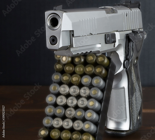 pistol and cartridges standing on a surface against a dark background