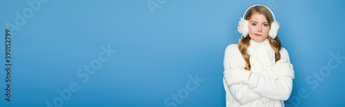 beautiful woman in winter white outfit feeling cold isolated on blue, banner