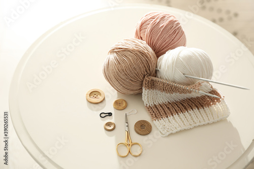 Yarn balls and knitting accessories on white table. Creative hobby