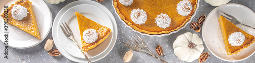 Traditional Autumn Pumpkin Pie. Homemade American Pumpkin pie topped with Whipped Cream. Rustic wooden table bakcground with Cozy plaid and sweater.