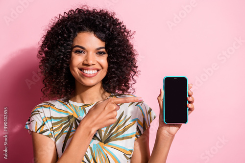 Photo portrait of woman pointing finger at phone in hand with blank space isolated on pastel pink colored background