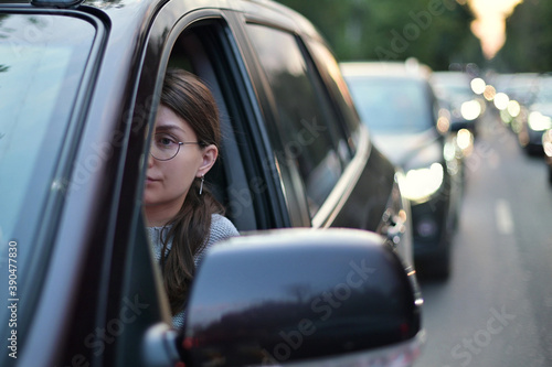 A young woman sits in a car during rush hour