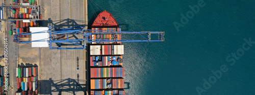 Aerial top down ultra wide photo of industrial cargo container ship loading in logistics terminal port
