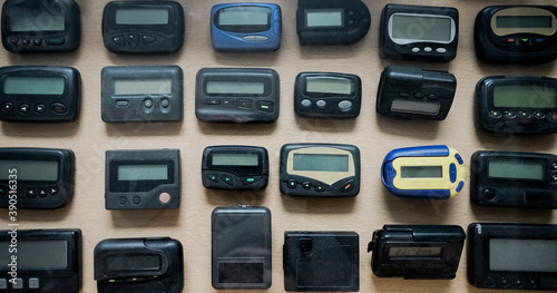  many, a lot old a black pagers or beepers on wooden background. front view.