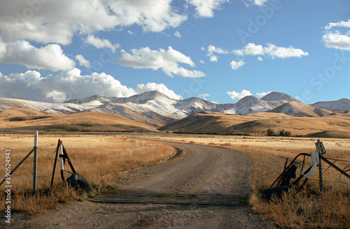 Montana Ranch entrance with road, hills, snow, and sky.