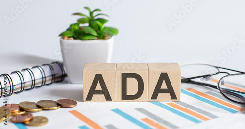 ADA word on wood blocks concept with chart, coins, notebook and glasses.