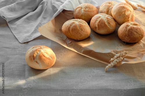 Kaiser or Vienna rolls on table covered with linen tablecloth.