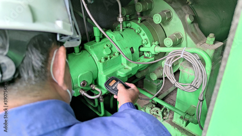 Inspector using a Handheld Vibration Tester for checking bearings and overall vibration of motor. Selective focus on inspection area.