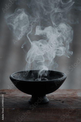 Vertical shot of a burning incense in a black bowl