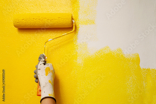 Roller Brush Painting, Worker painting on surface wall Painting apartment, renovating with yellow color paint. Leave empty copy space white to write descriptive text beside.