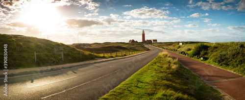 Road to iconic lighthouse surrounded by houses during sunset at the island of Texel, The Netherlands