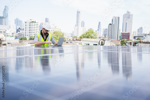 Rooftop solar power plant engineers sitting and examining photovoltaic panels. Concept of alternative energy and its service. Electrical and instrument technician use laptop to maintenance electric 