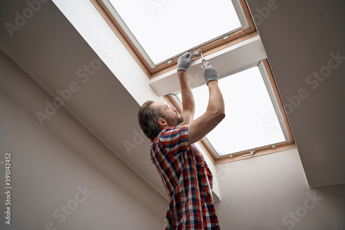 Young caucasian worker screwing skylight window handle