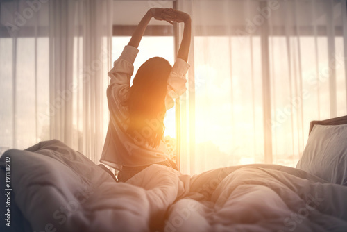 Woman stretching hands in bed after wake up in the morning, Concept of a new day and joyful weekend.