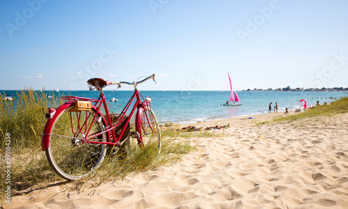 Vieux vélo rouge en bord de plage sur le littoral français.